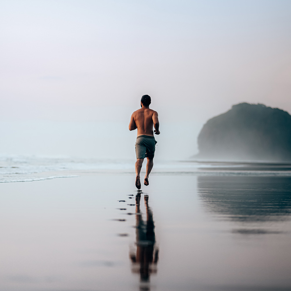 Hombre corriendo por una playa al amanecer